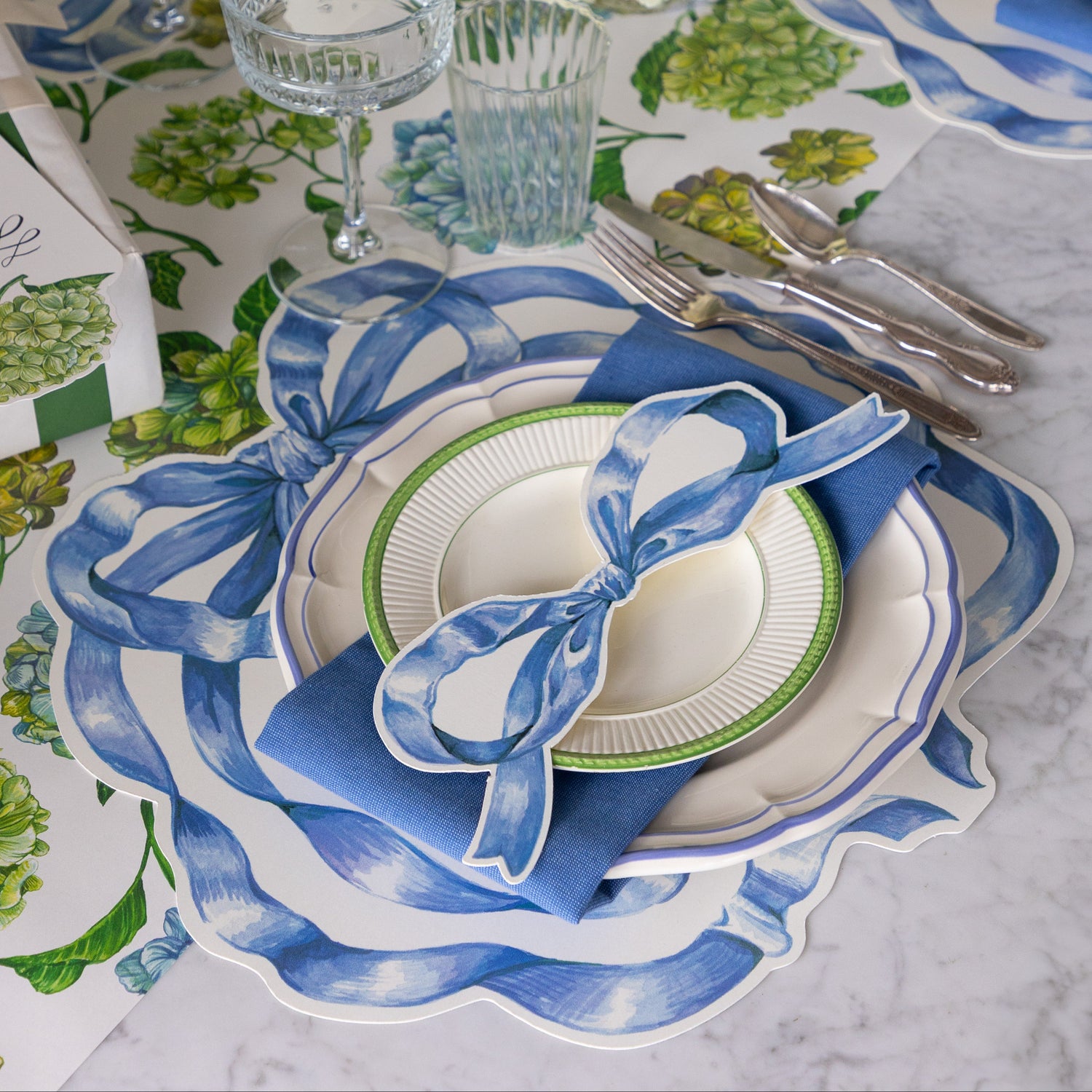 Elegant table setting with the Die-cut Heirloom Blue Bow Placemat, Heirloom Blue Bow Table Accent and blue napkin on the Hydrangea Runner.