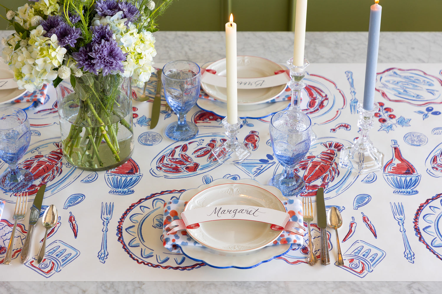 Decorative table runner with a floral arrangement, candles, and patterned tablecloth.