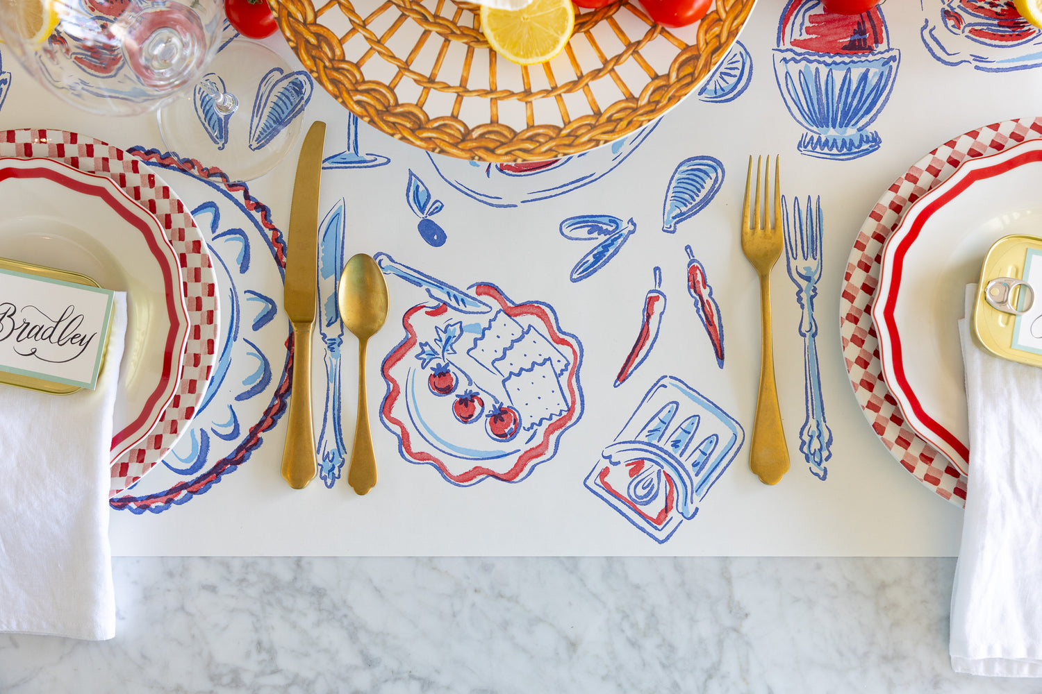 Dining table setting with decorative placemat, plates, and cutlery on a marble surface.