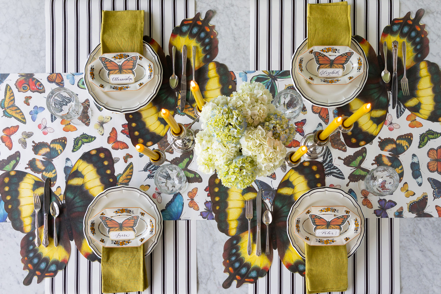 Butterfly-themed table setting flowers, candles, Die-cut Butterfly Placemats, Butterfly Place Card and Black Icing on  the Cake plates on the Butterflies and Black Linen Stripe Runners.