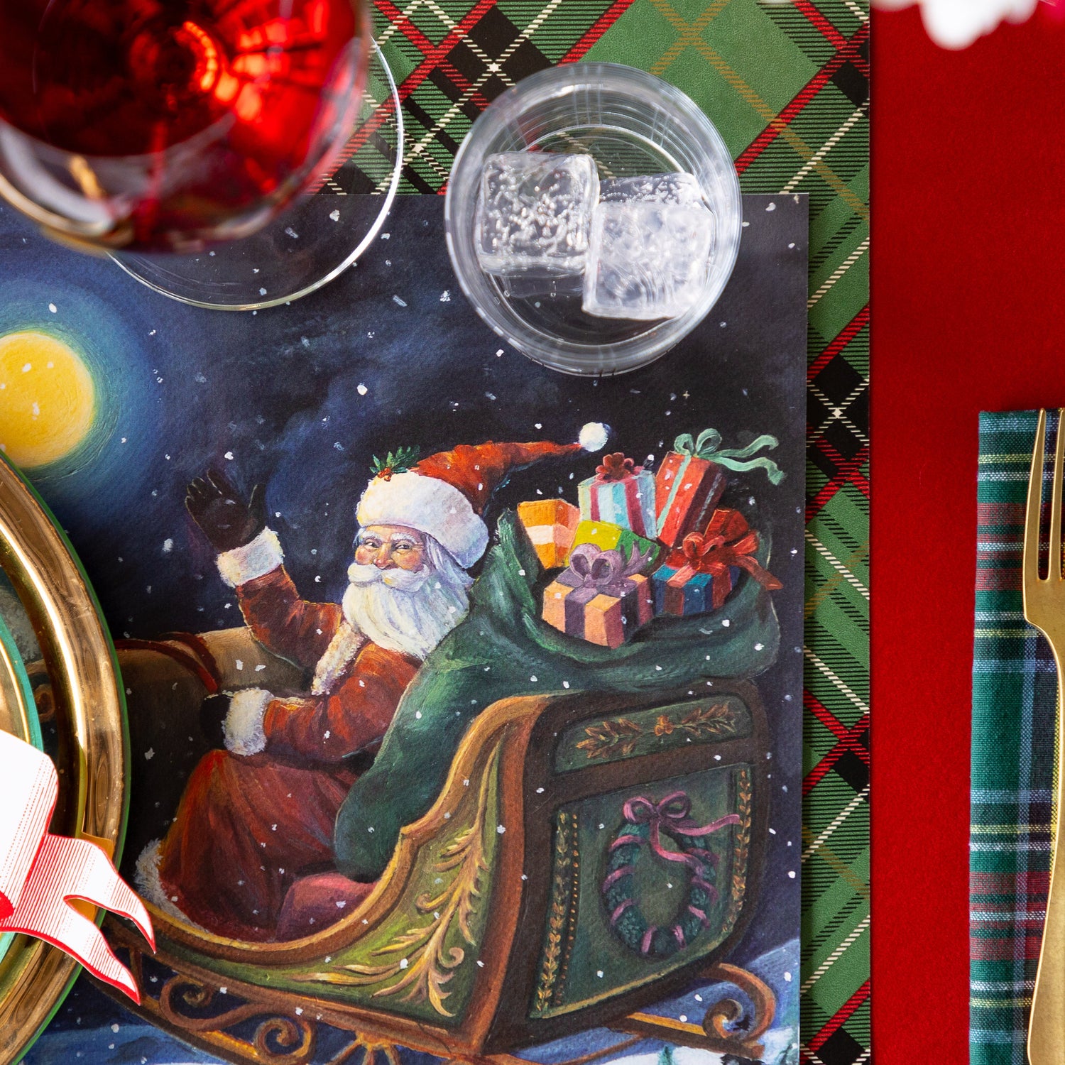 A close up of the Sleigh Ride Placemat under a place setting, showing Santa Claus in his sleigh with a sack of presents, waving.