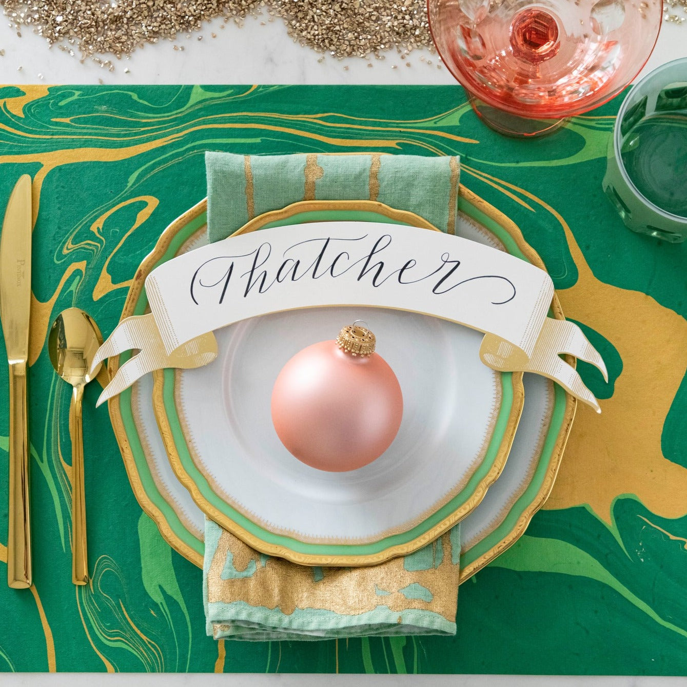 The Green &amp; Gold Vein Marbled Placemat under a festive holiday-themed place setting, from above.