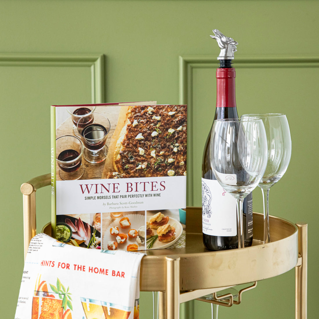 Wine Bites book displayed on a bar cart with wine glasses and a bottle of wine