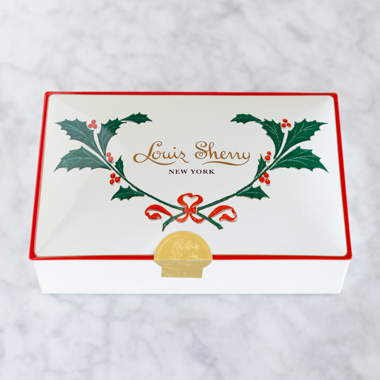 Louis Sherry New York box with holly design on a white background.