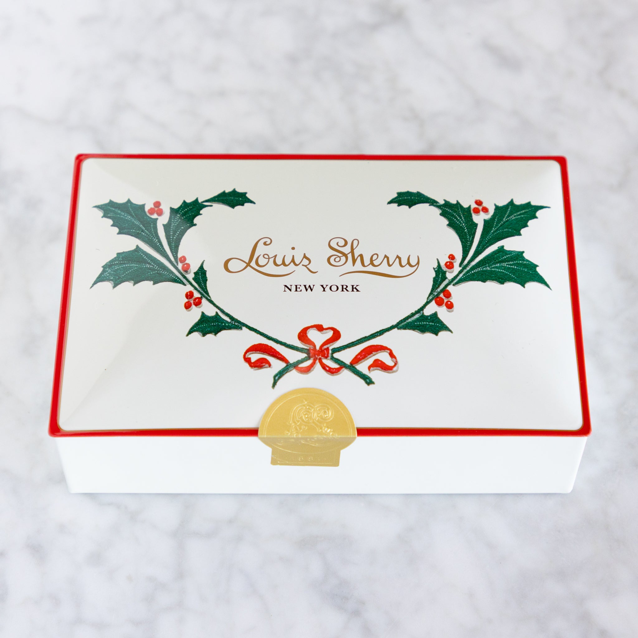 Louis Sherry New York box with holly design on a white background.