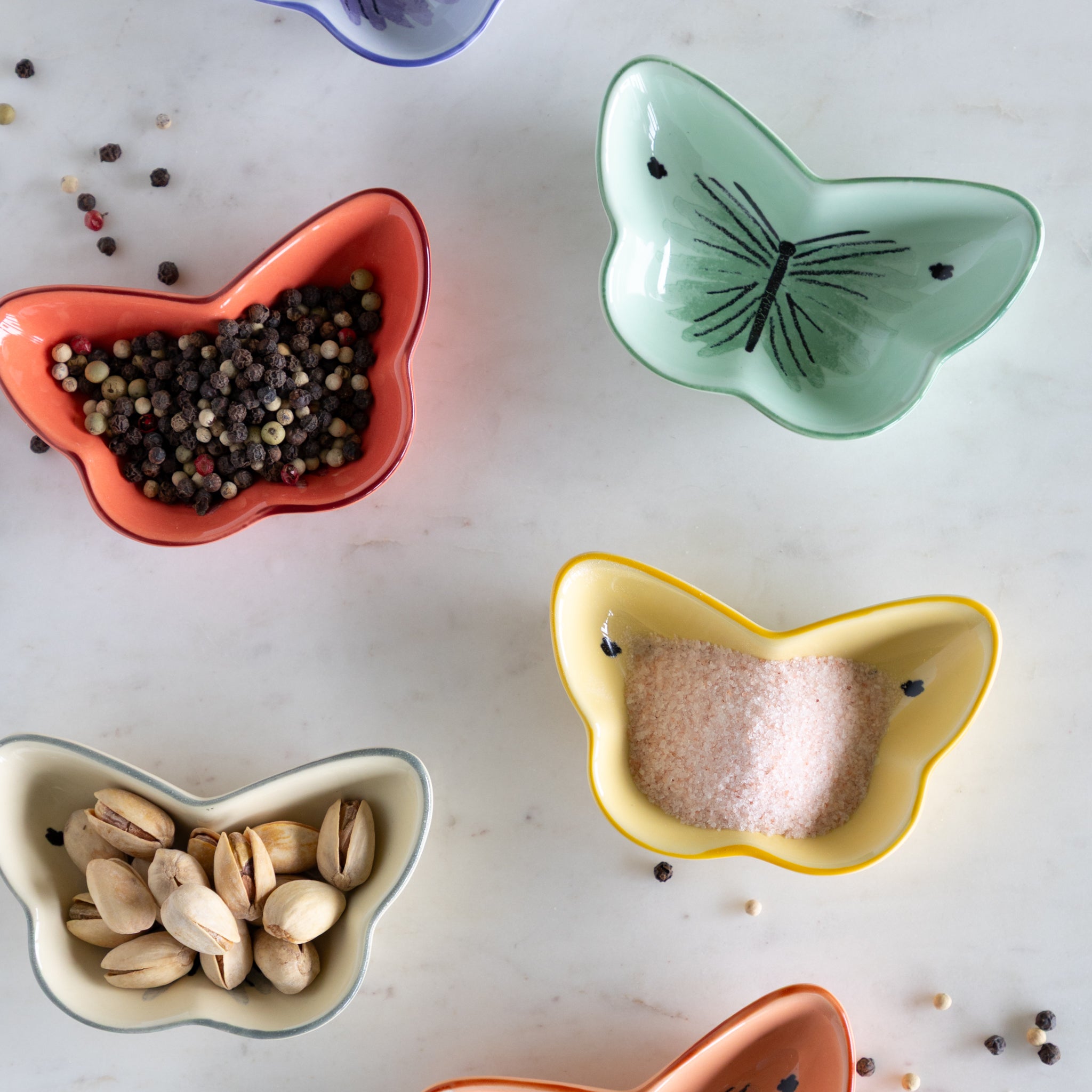 Butterfly-shaped ceramic bowls with various contents on a light surface.