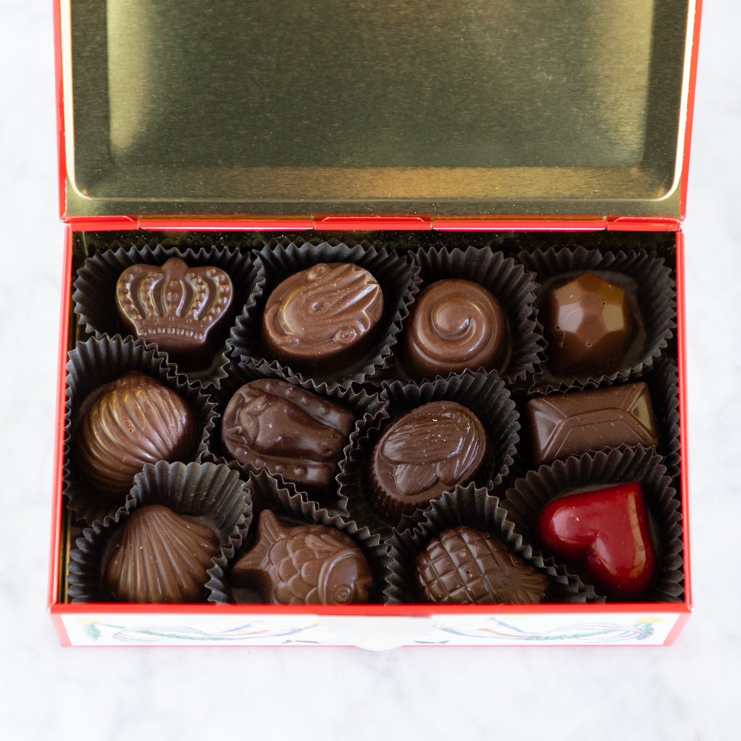 Box of assorted chocolates with a heart-shaped chocolate on a white background.
