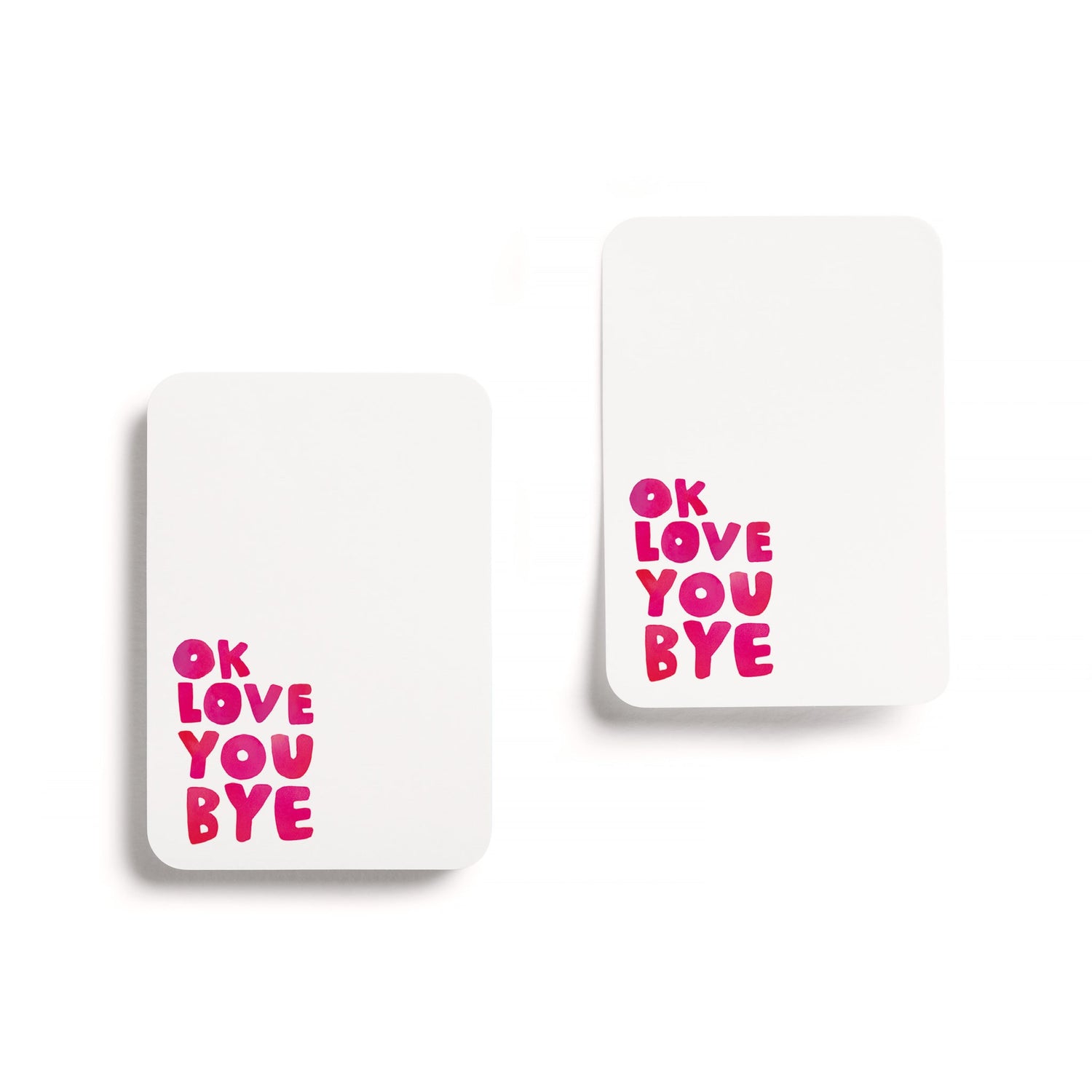 Two square post its with pink text saying ok love you bye on a white background.