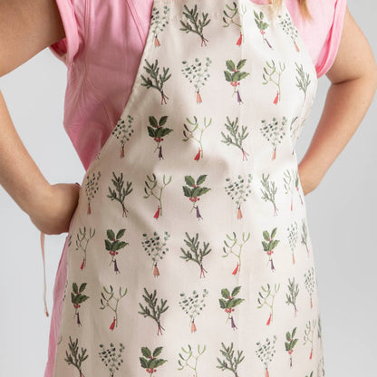 A woman tying the Laura Stoddart Christmas Apron behind her back.