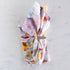 Colorful floral-patterned napkin with a metal napkin ring on a light marble background.