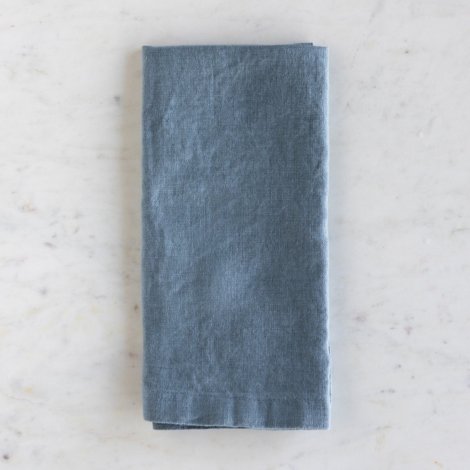 Folded blue napkin on a light marble surface.