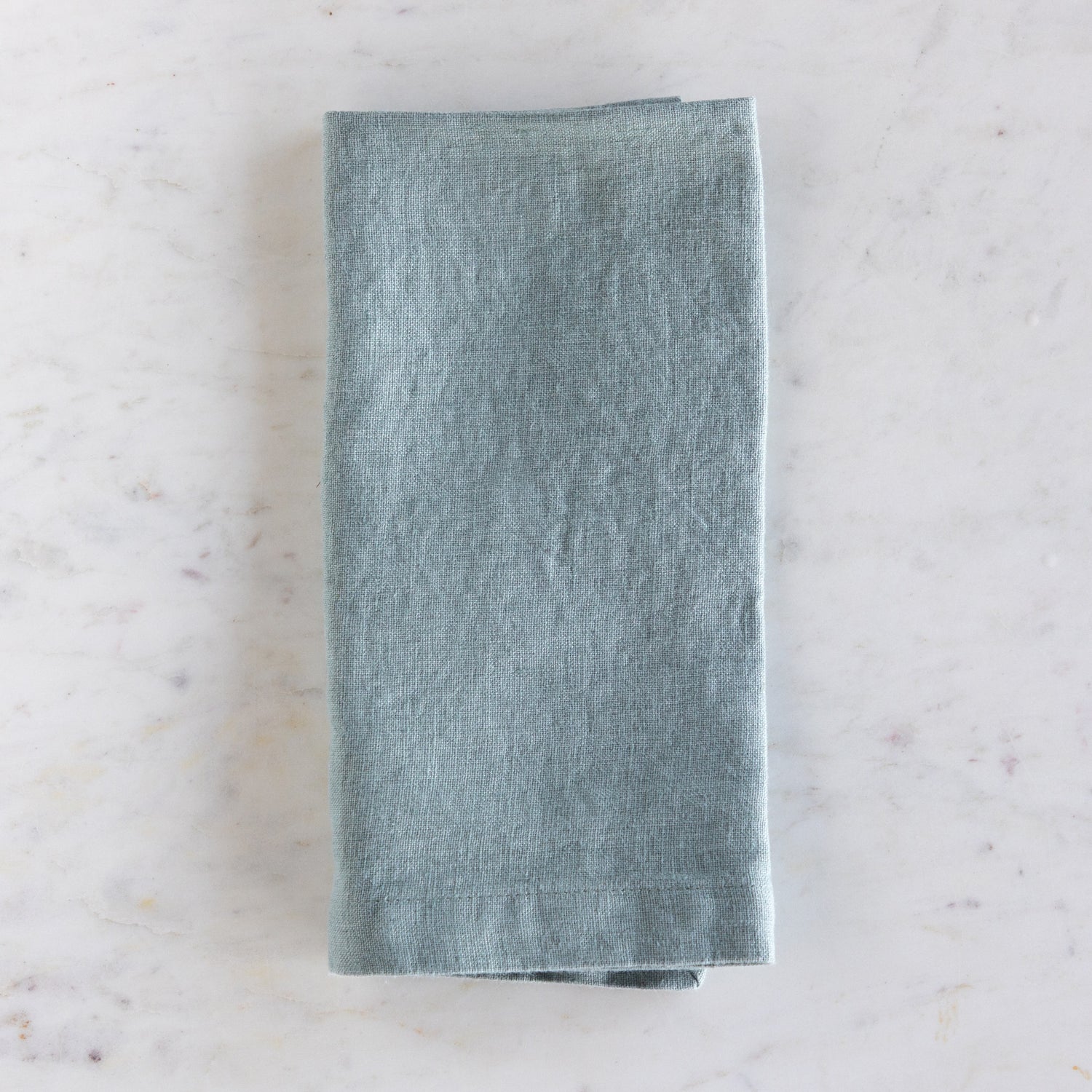 Folded green napkin on a marble surface.