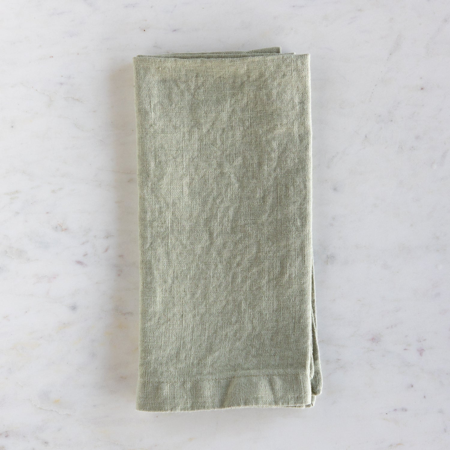 Folded green napkin on a marble surface.