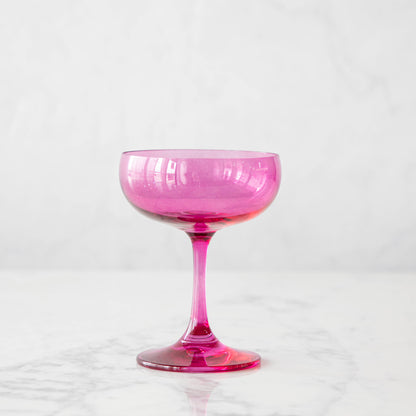 A pink crystal stemware wine glass on a marble table.