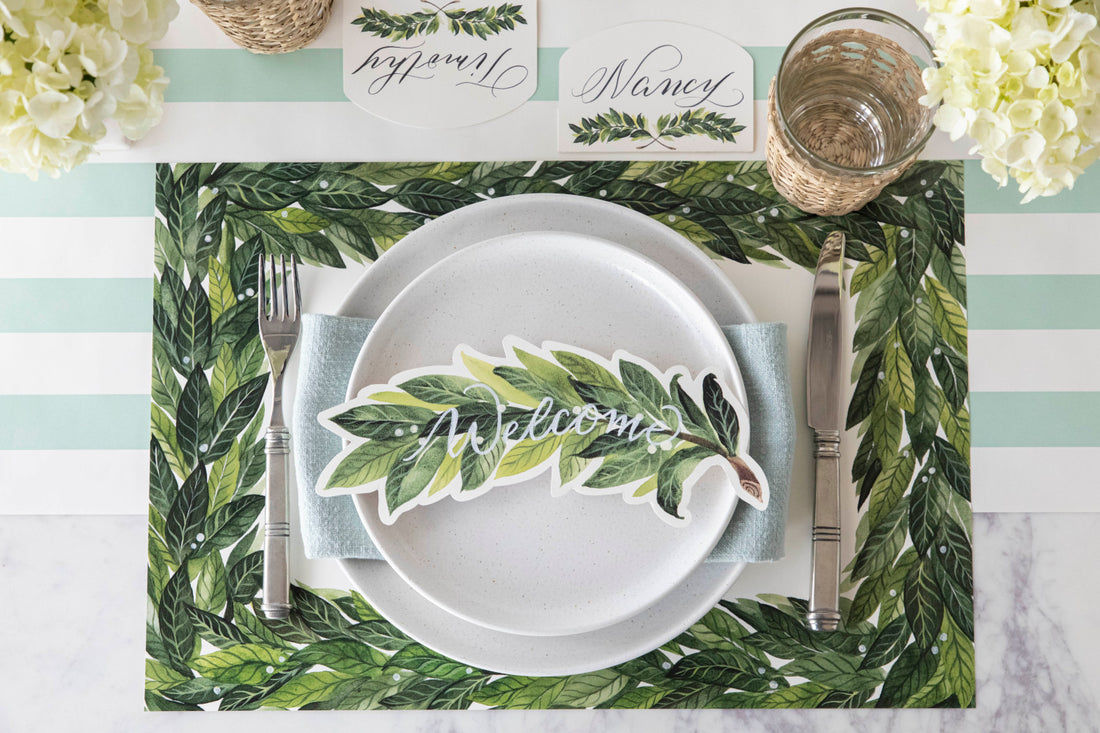 An elegant table setting with green leaves and a Laurel Table Accent placemat by Hester &amp; Cook.