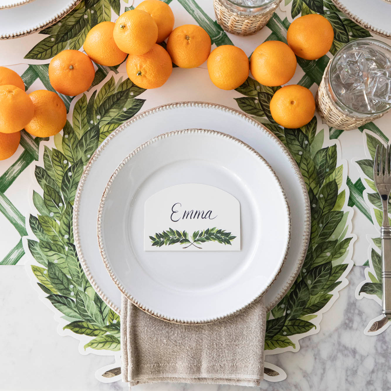 Die-cut Laurel Placemat on the Green Lattice Runner on a place setting, with oranges arranged down the center of the table.