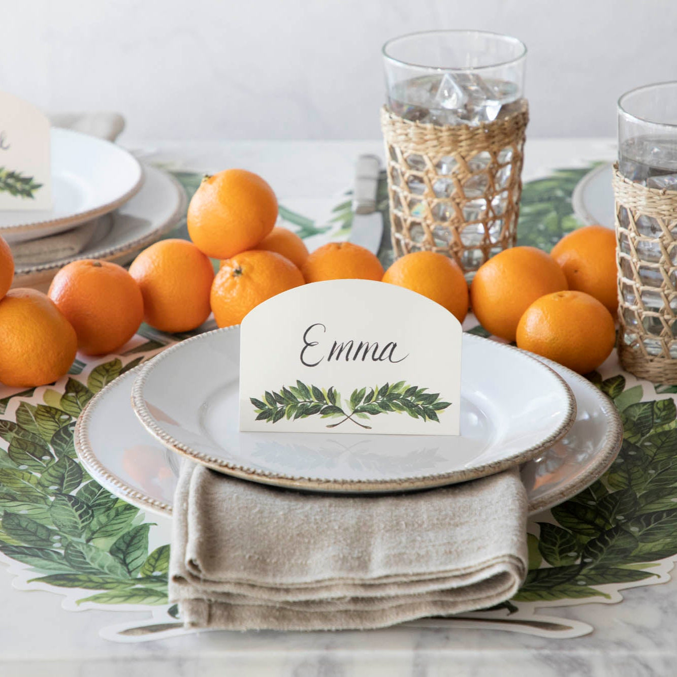 Laurel Place Card with &quot;Emma&quot; written on it, resting on dinner plates on a laurel themed table setting.