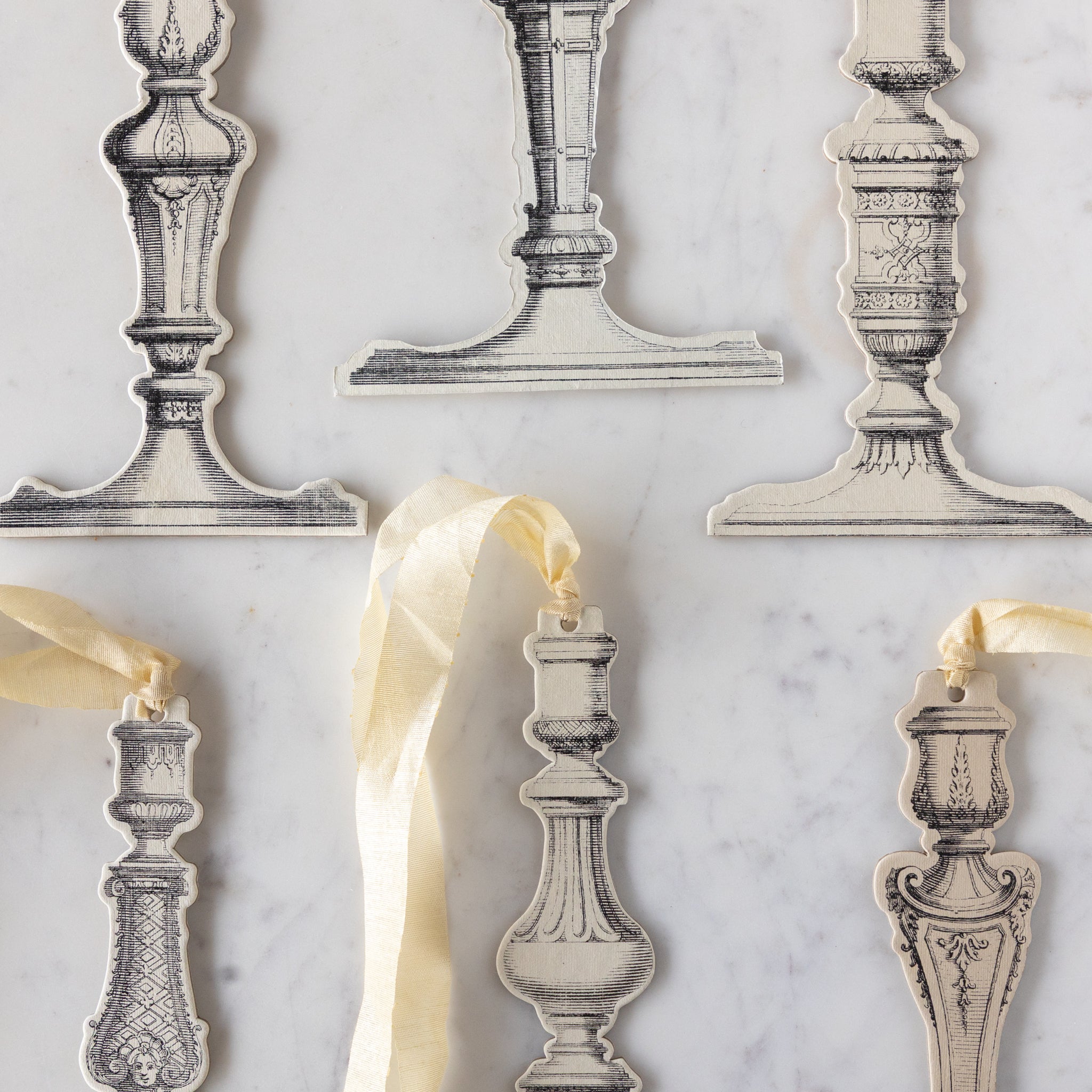 Decorative candlestick holders with ribbons on a marble surface.