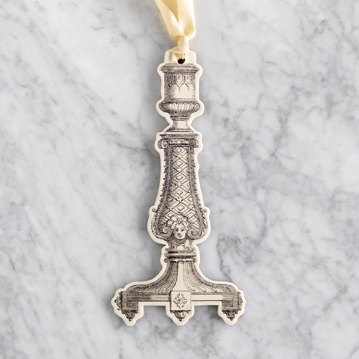 Decorative candlestick ornament on a marble background.