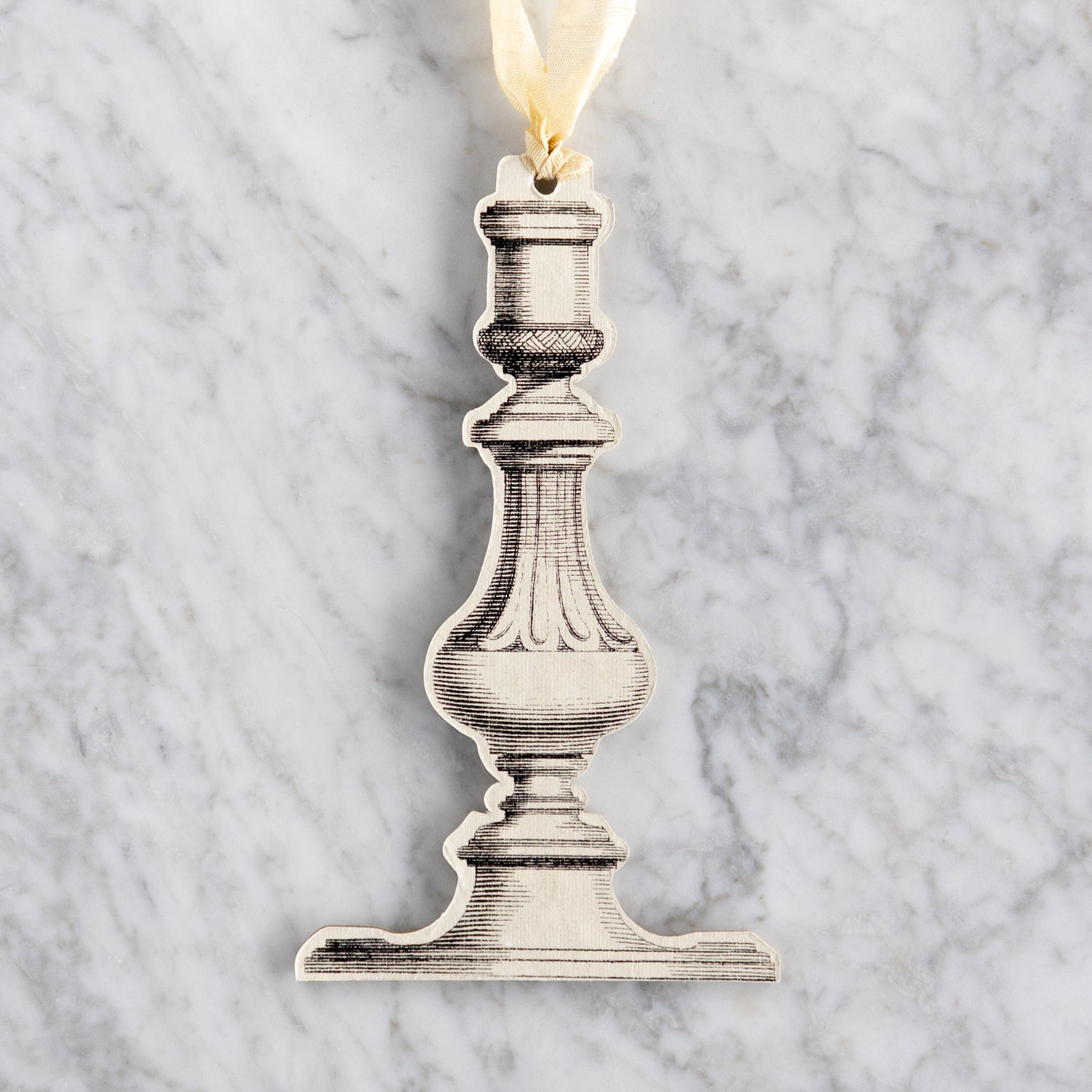 Decorative metal candlestick ornament on a marble background.