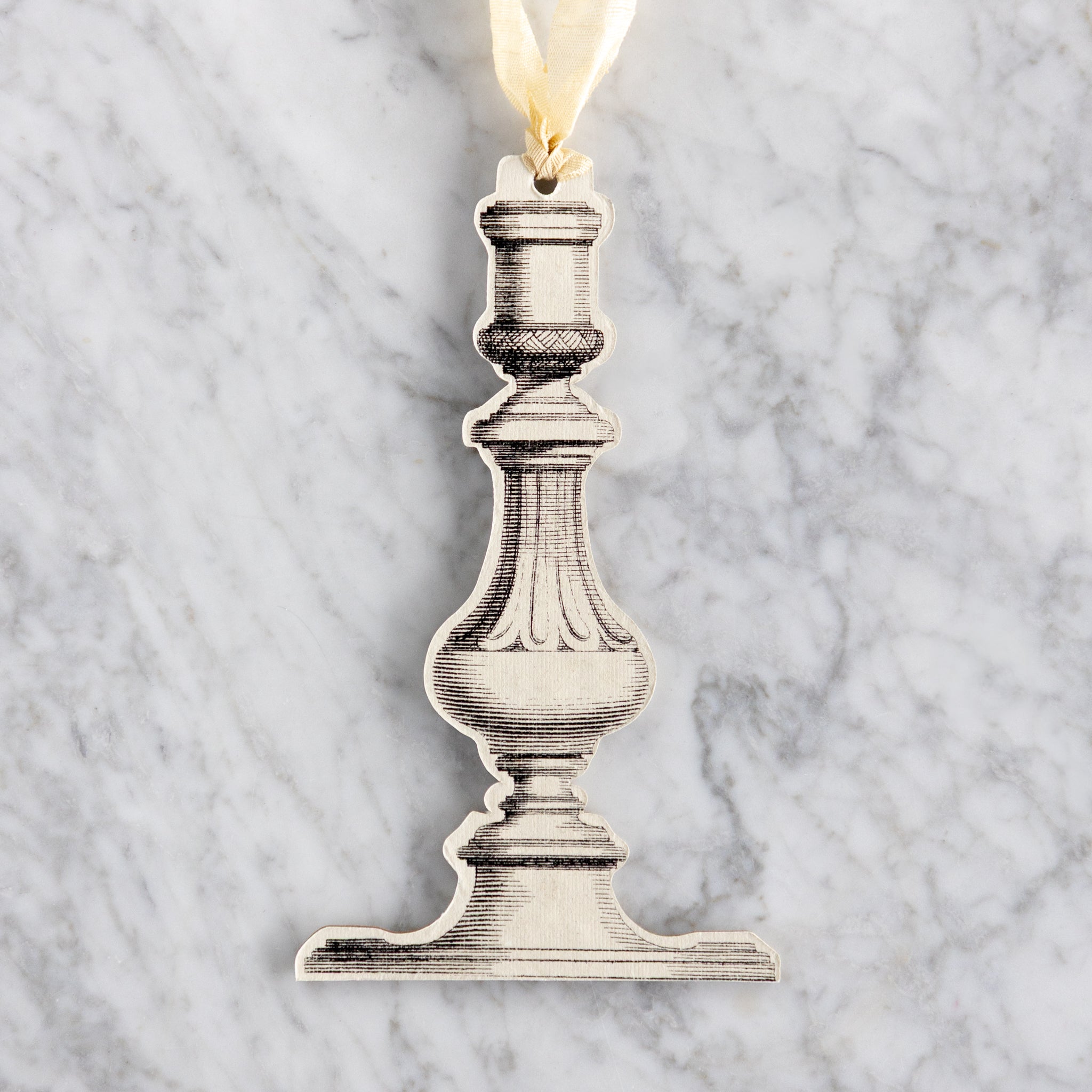 Decorative metal candlestick ornament on a marble background.