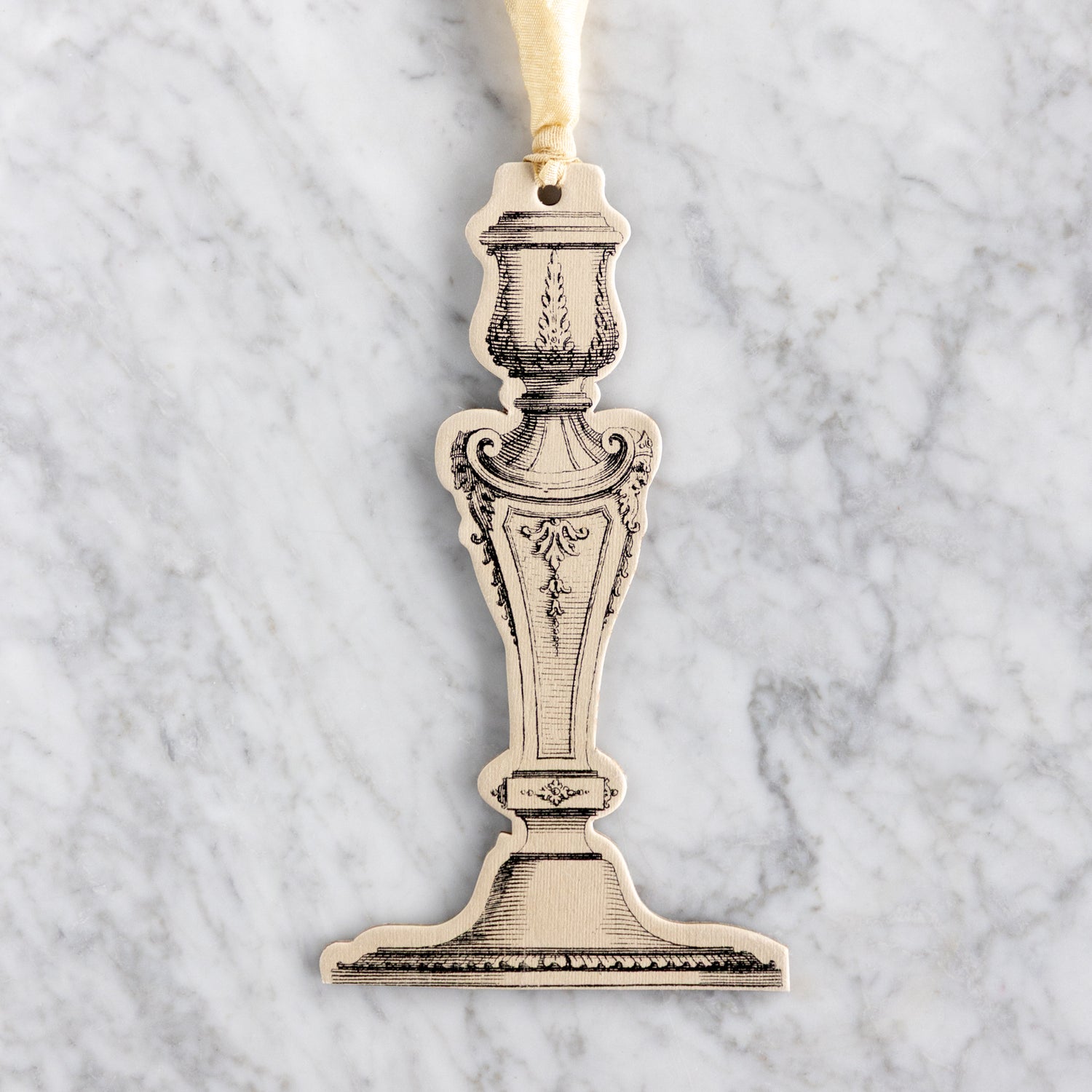 Decorative paper candlestick ornament on a marble surface.