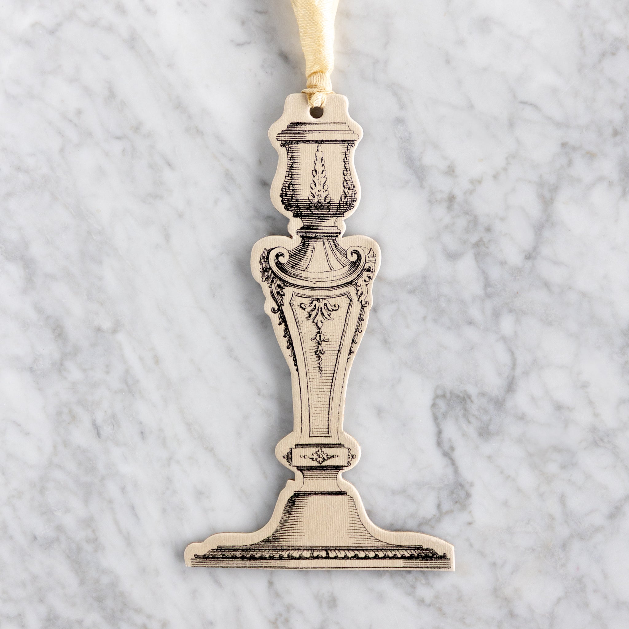 Decorative paper candlestick ornament on a marble surface.