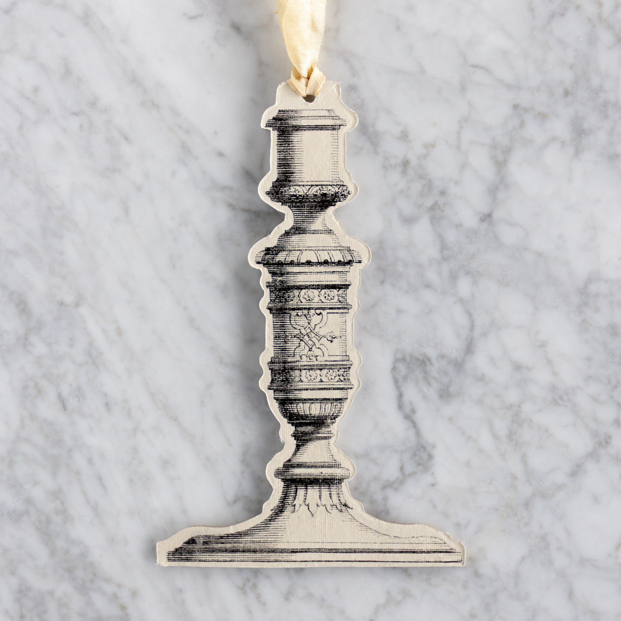Decorative candlestick ornament on a marble background.