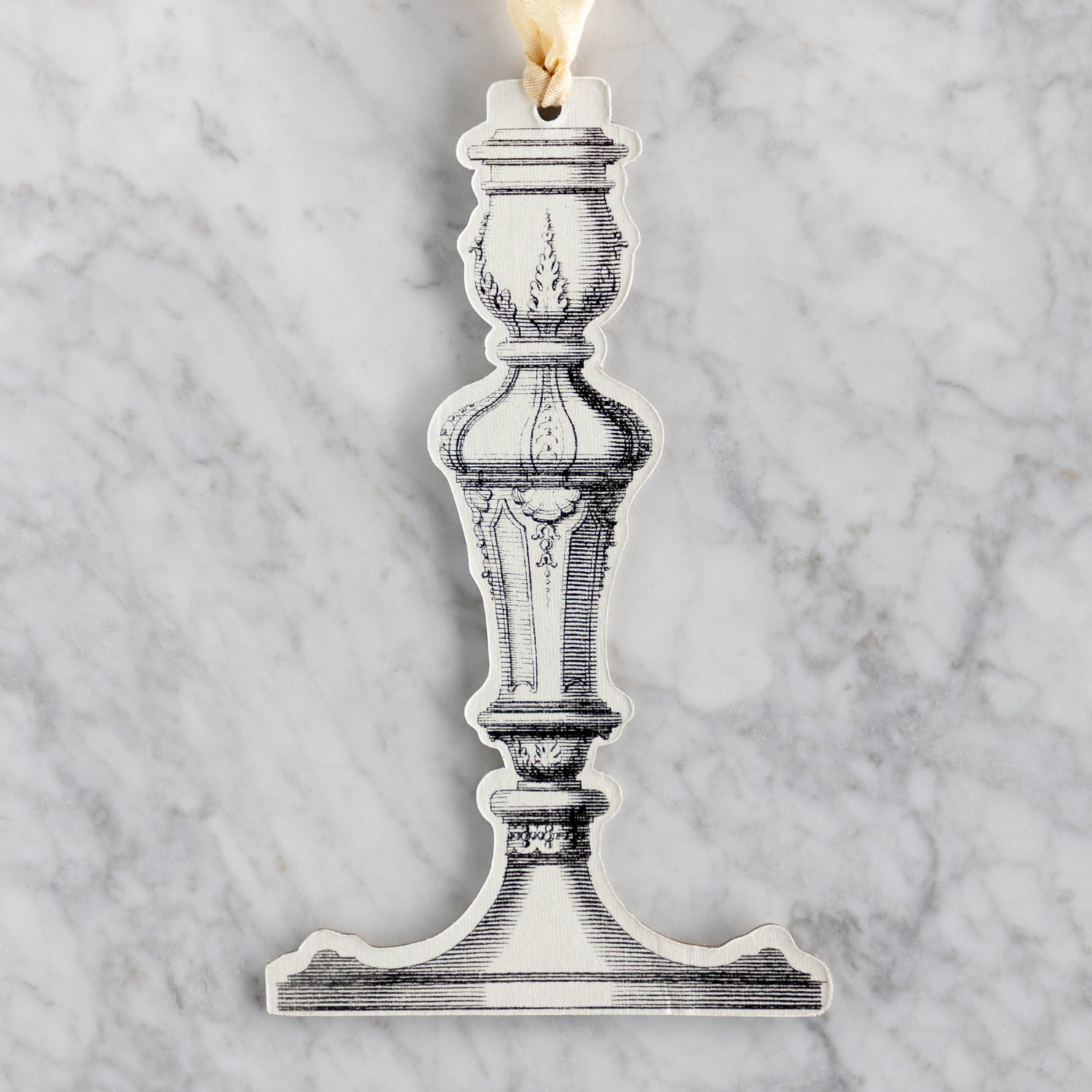 Decorative candlestick ornament on a marble background.