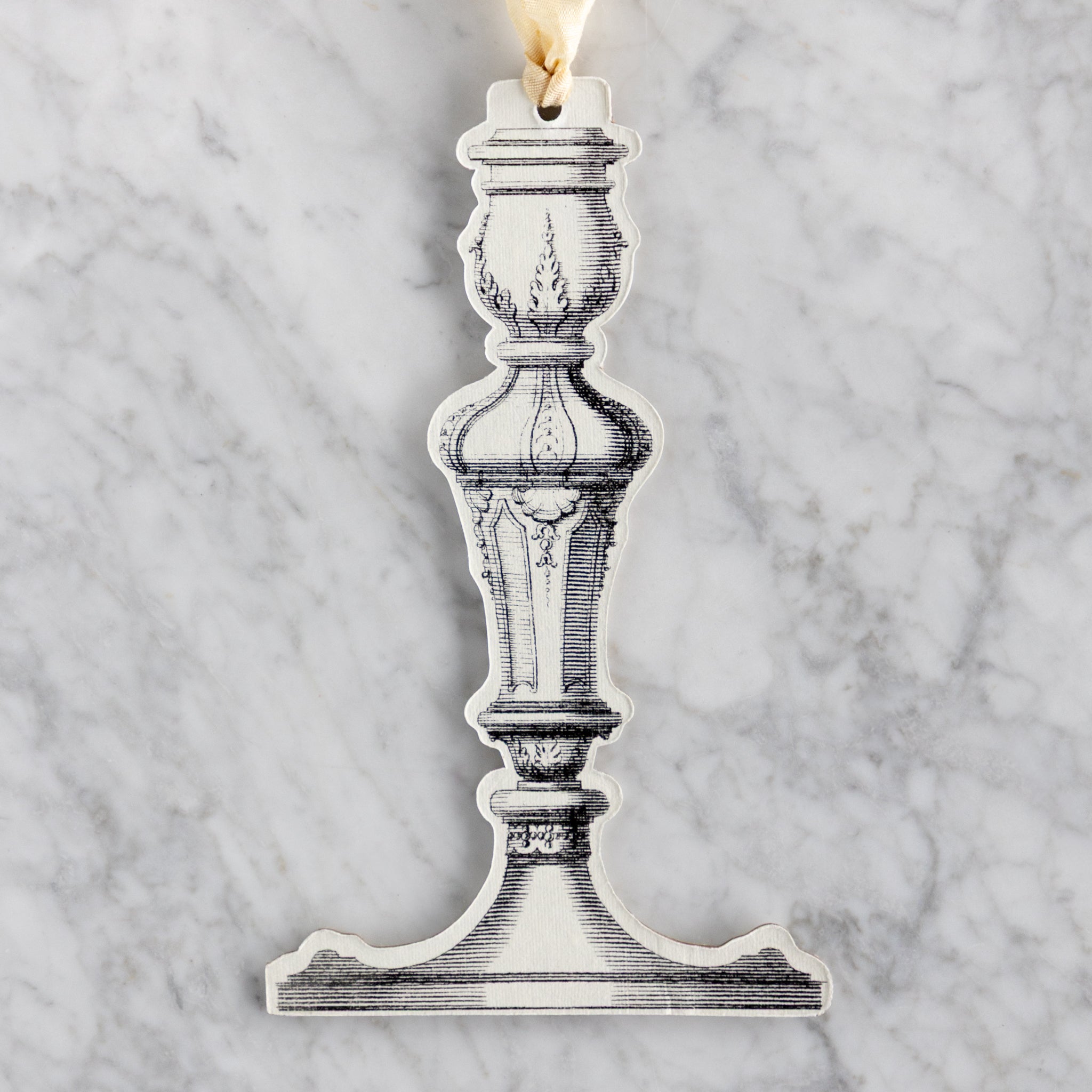 Decorative candlestick ornament on a marble background.