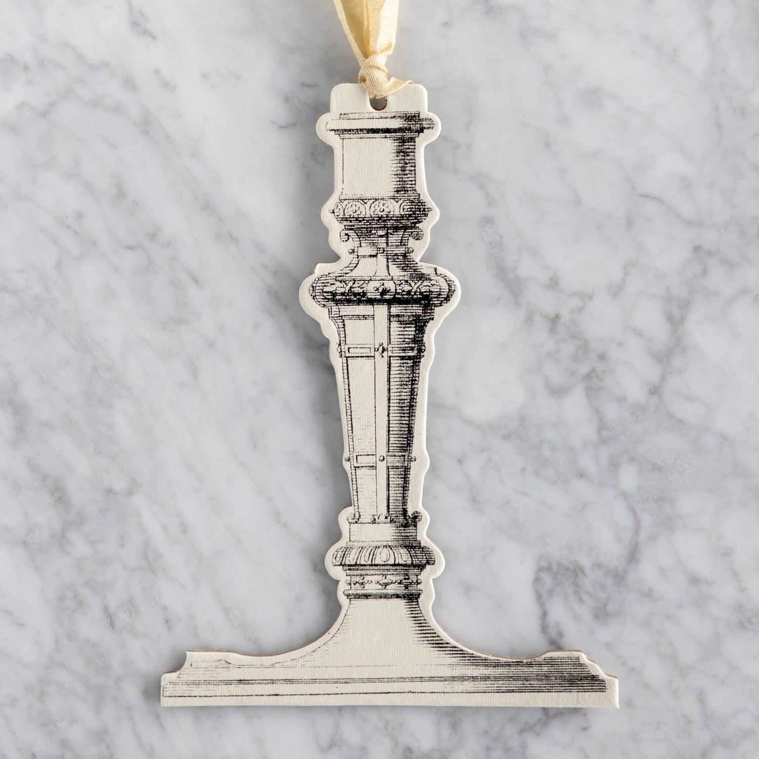 Decorative candlestick ornament on a marble background.