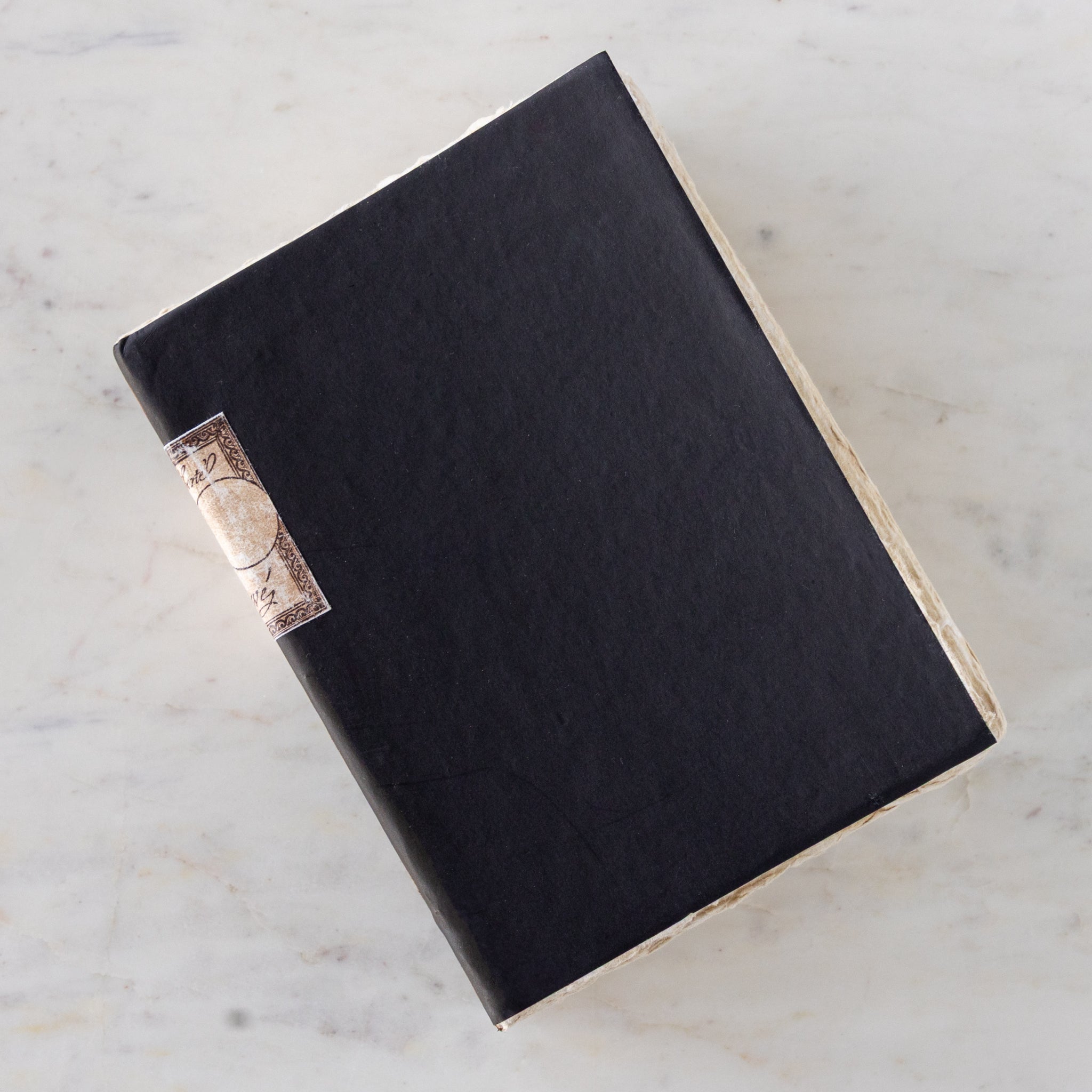Large Handmade Paper Notebook with a blue cover, decorative binding and vintage torn paper edges on a marble table.