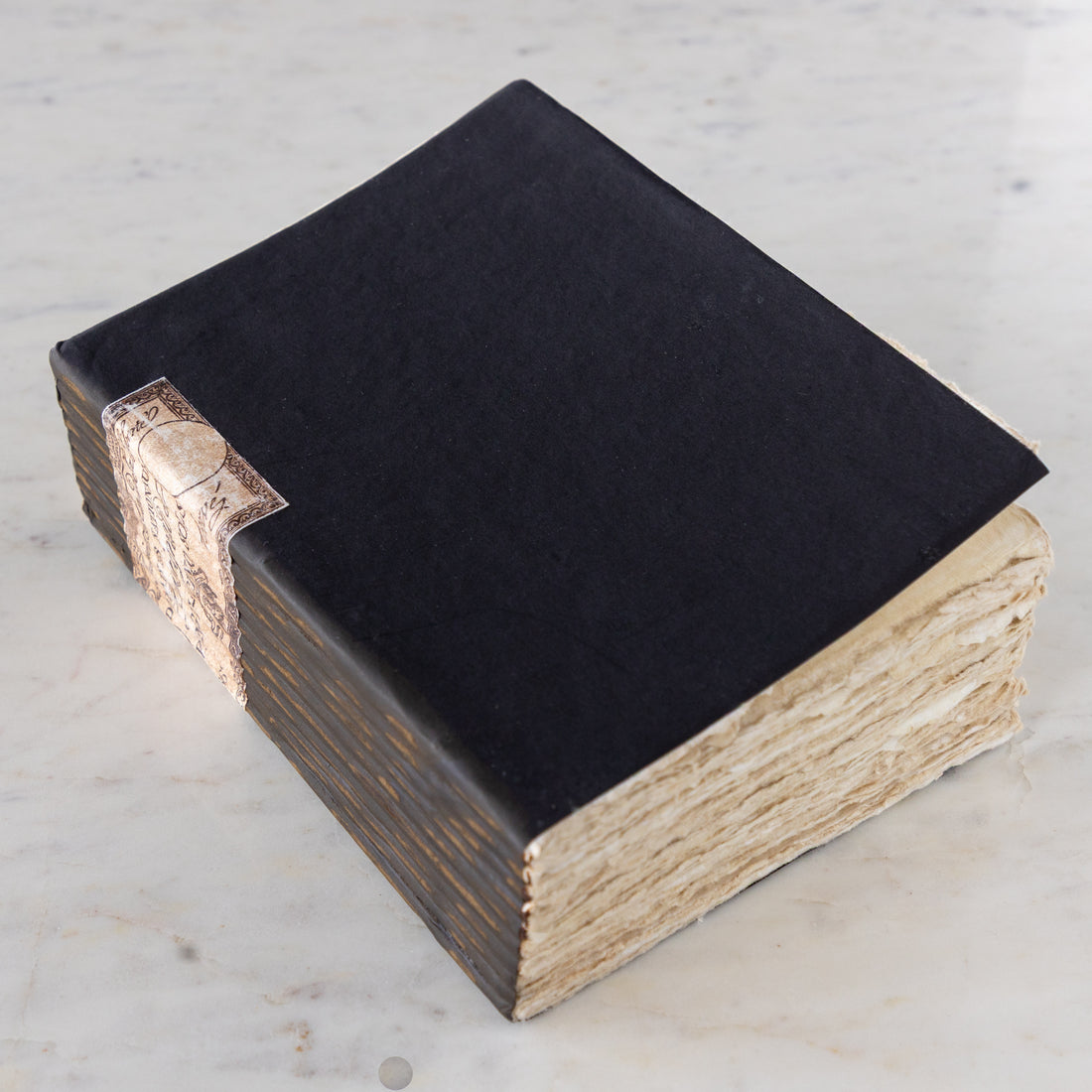 Large Handmade Paper Notebook with a blue cover and vintage torn paper edges on a marble table.