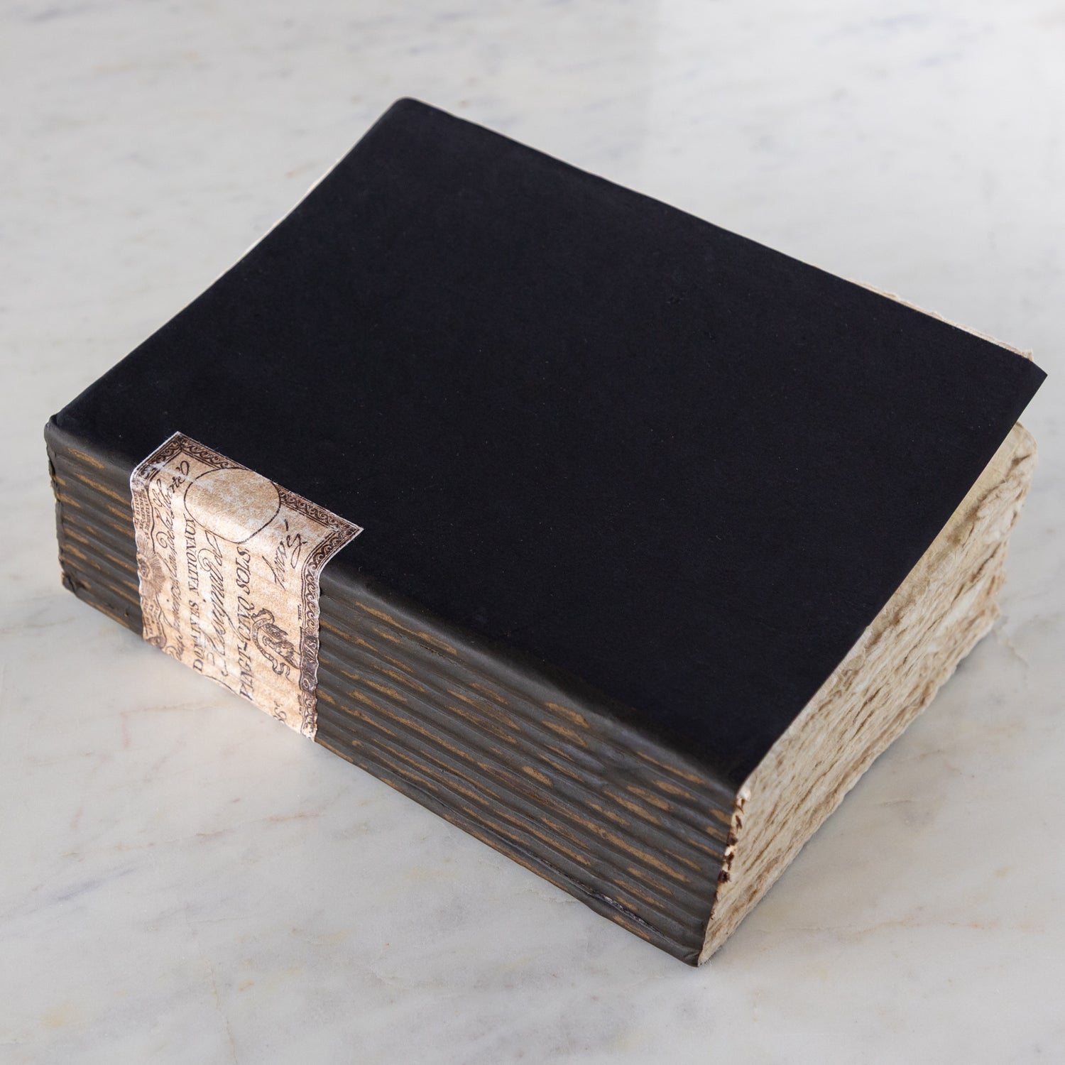 Large Handmade Paper Notebook with a blue cover, decorative binding and vintage torn paper edges on a marble table.