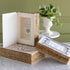 Decorative storage boxes resembling vintage books displayed on a marble table with a plant behind.