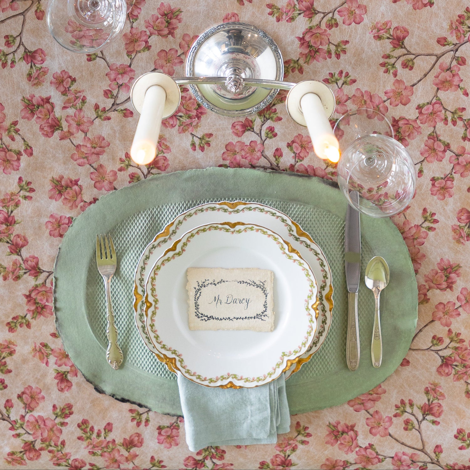 Elegant table setting with a green paper placemat, candles, and silverware on the Pink Cherry Blossom Runner.