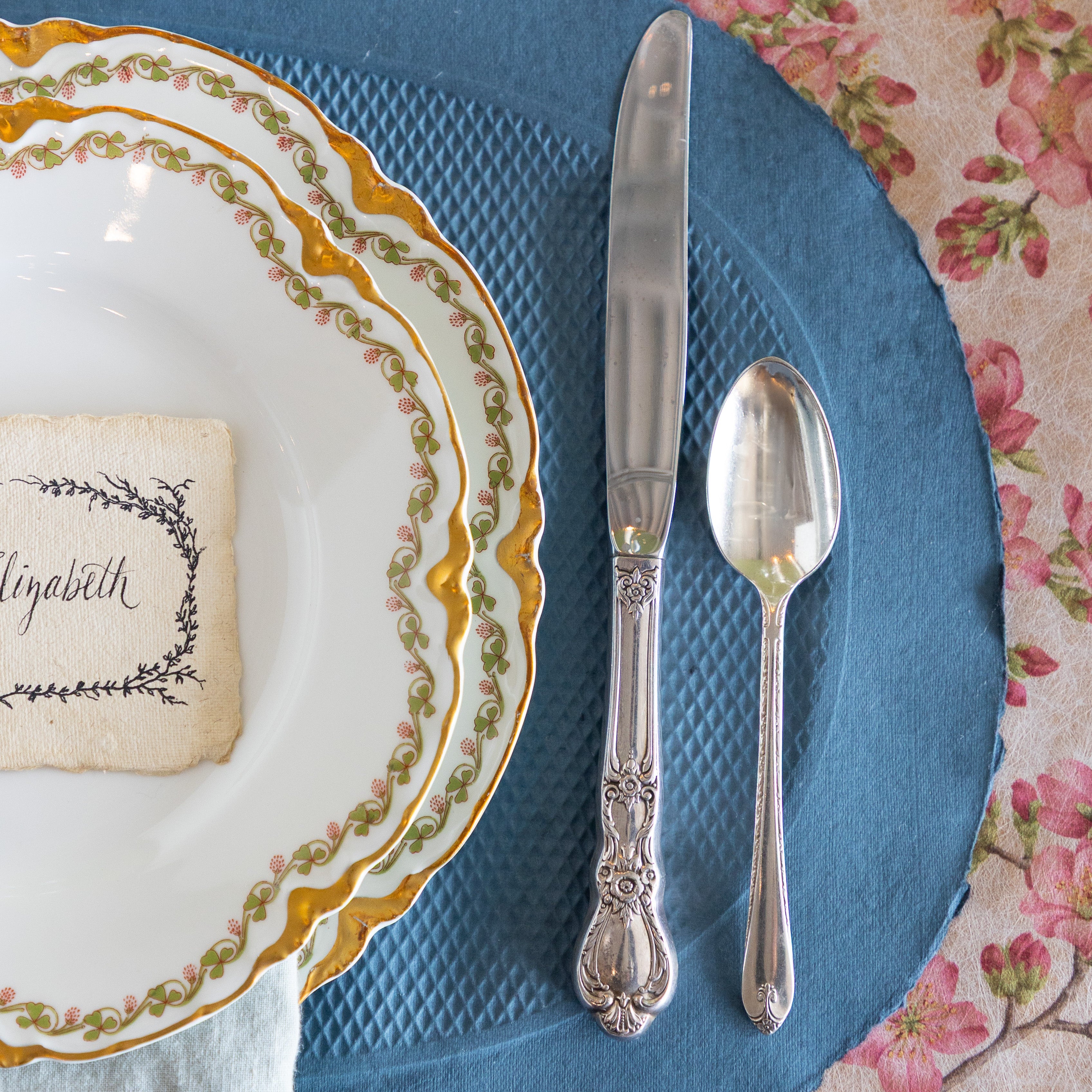 A close up a blue paper placemat under an elegant place setting.