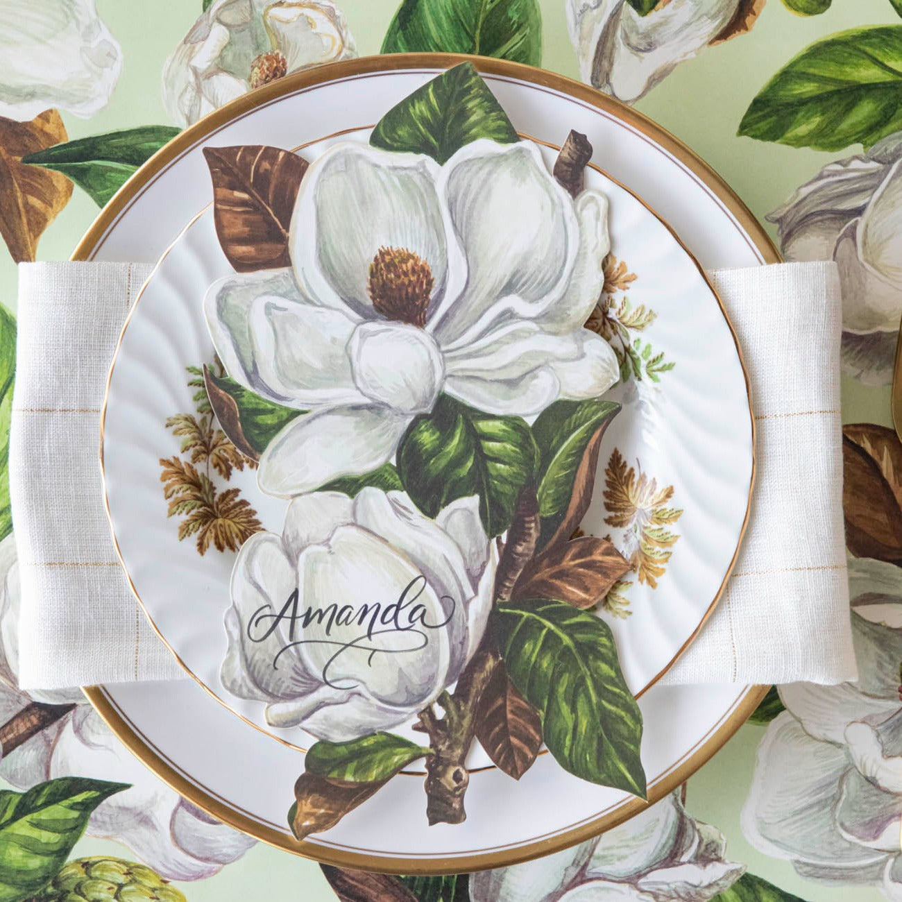 An elegant place setting featuring a Magnolia Blooms Table Accent with &quot;Amanda&quot; written in beautiful script resting on the plate.