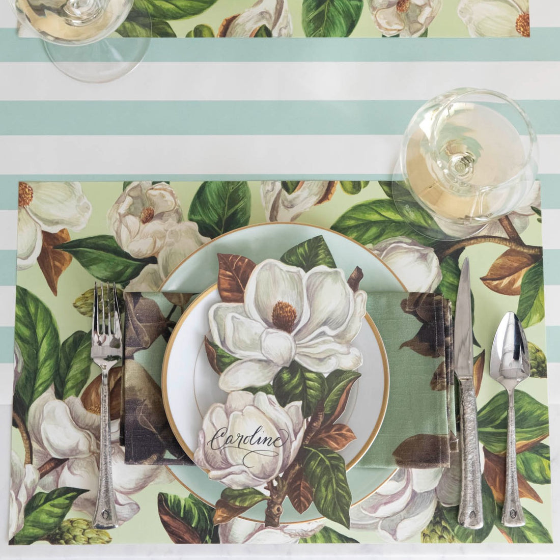 The Mint Magnolia Blooms Placemat under an elegant table setting, from above.