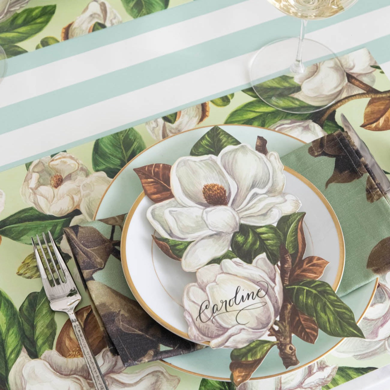 The Mint Magnolia Blooms Placemat under an elegant table setting.