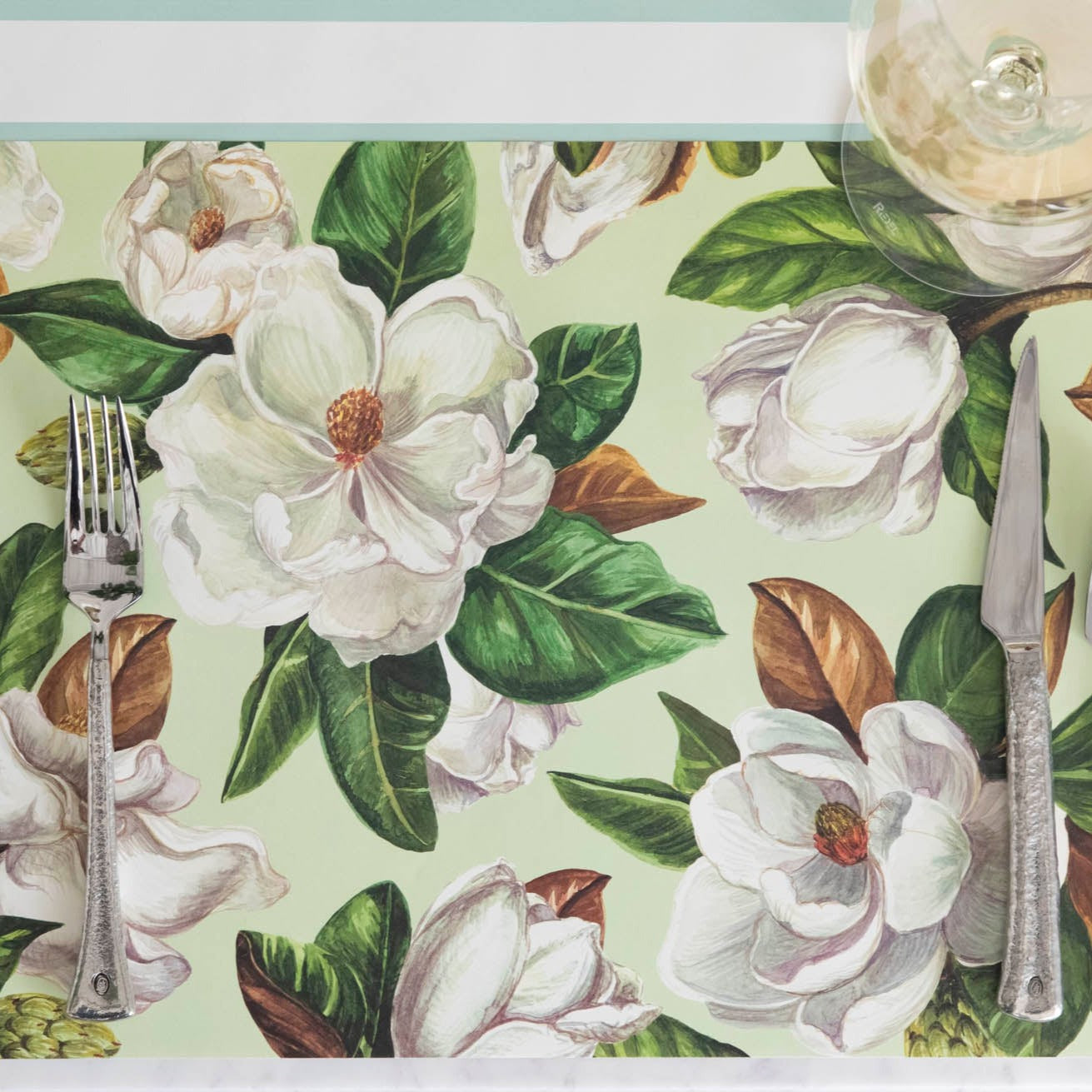 The Mint Magnolia Blooms Placemat under an elegant place setting, from above.