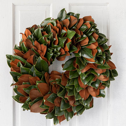 A fresh Magnolia wreath hanging on a door.