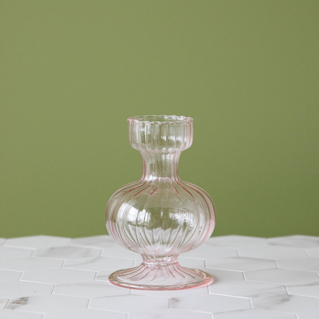 A Pink Vintage Boutique Vase from Accent Decor with a pink glass design sitting on top of a marble table.