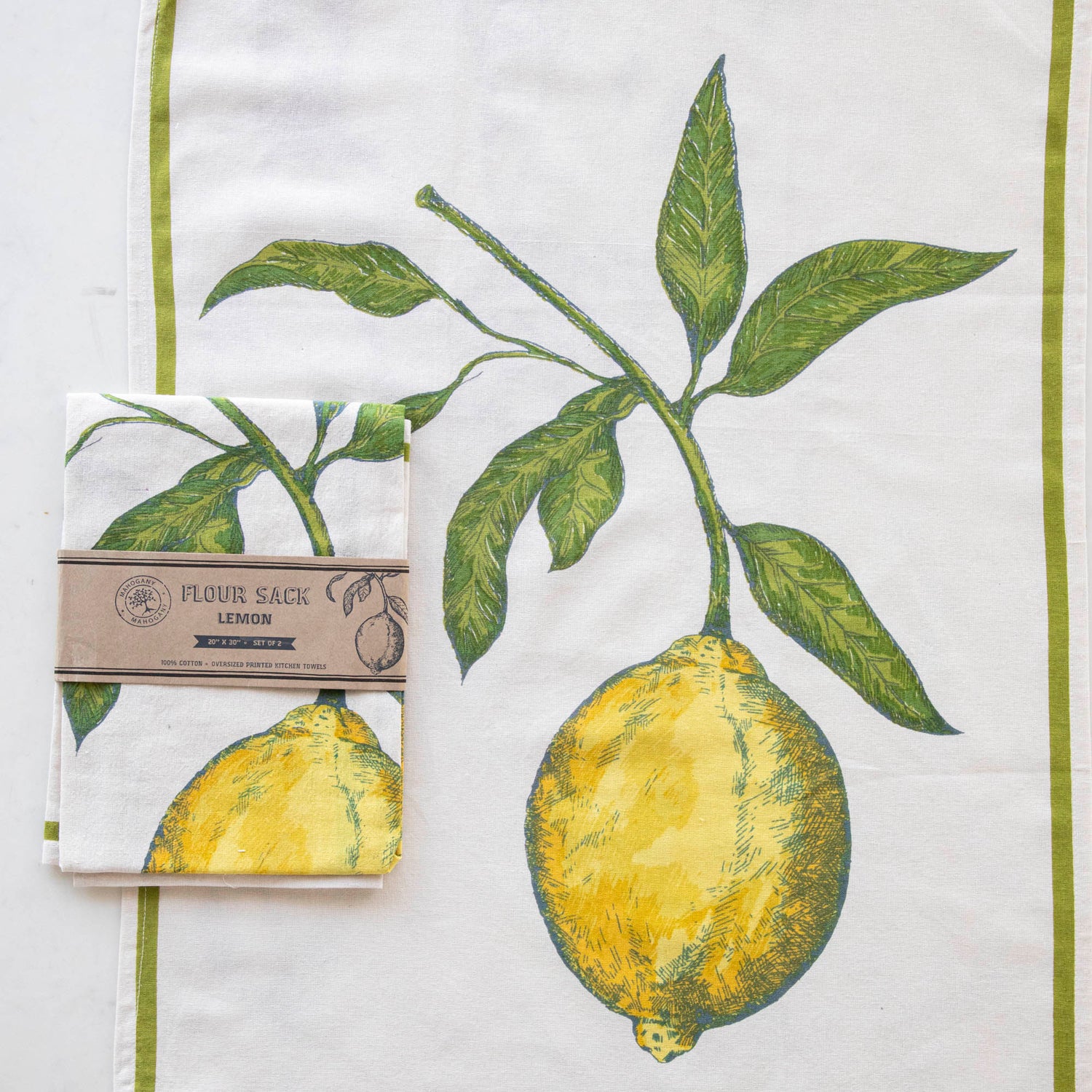 A Lemon Flour Sack Kitchen Towel Set of 2 with a lemon design hanging on a wooden deck railing, with a bowl of lemons in the background. (Mahogany)
