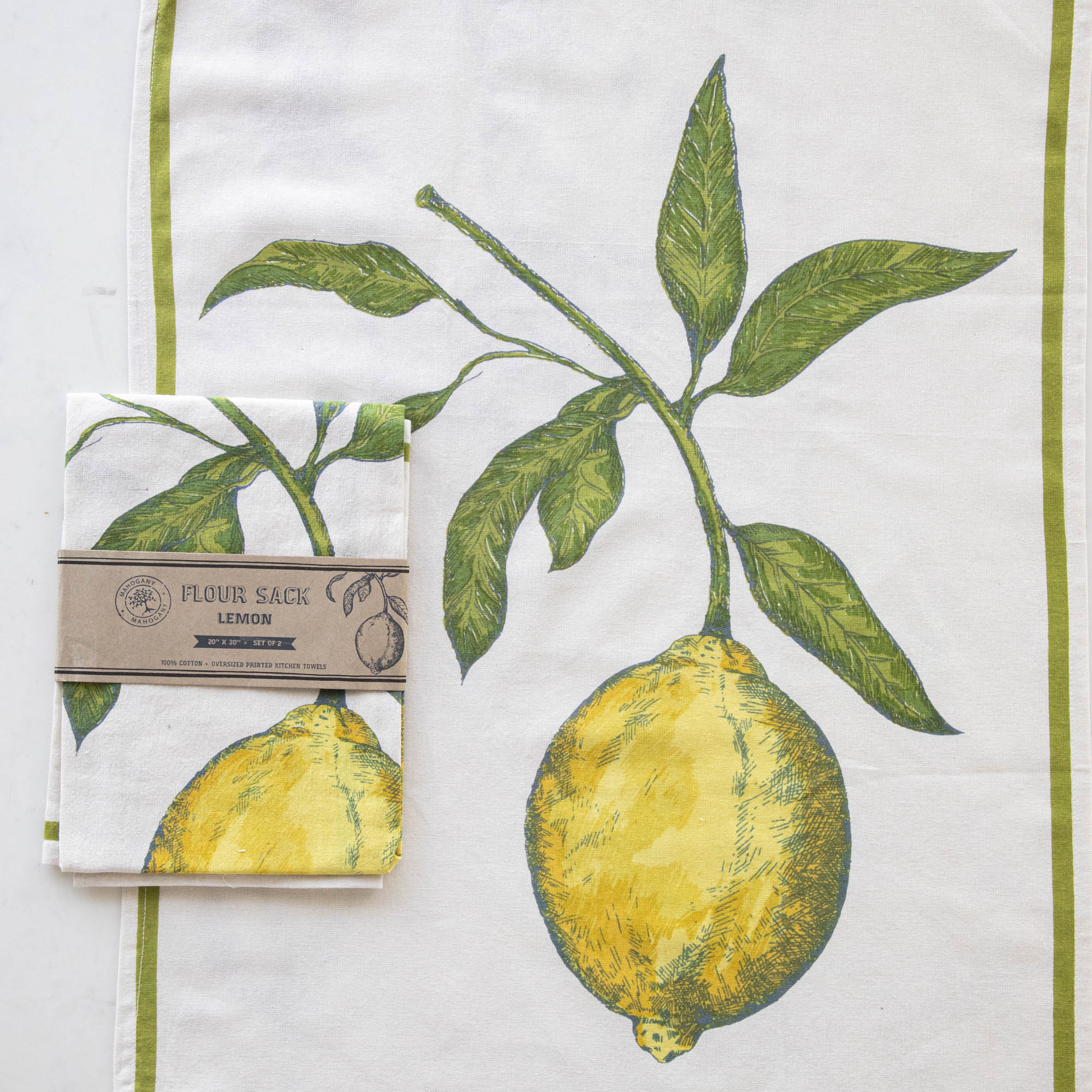 A Lemon Flour Sack Kitchen Towel Set of 2 with a lemon design hanging on a wooden deck railing, with a bowl of lemons in the background. (Mahogany)