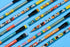 A set of colorful Disney-branded mechanical pencils arranged diagonally on a bright blue background. The pencils feature cartoon character prints including Mickey Mouse, Minnie Mouse, Pluto, and Goofy, with black erasers and black end caps.