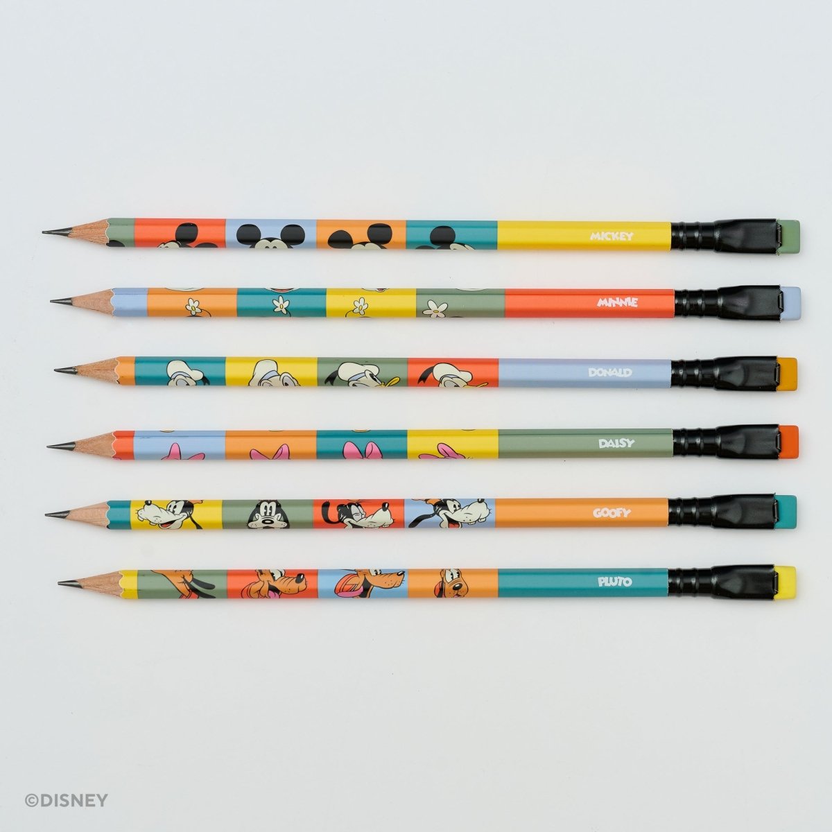Six colorful Disney-themed pencils arranged horizontally on a light gray background, featuring cartoon character designs and names including Mickey, Jane, Donald, Daisy, Goofy, and Pluto. A small Disney copyright mark appears in the lower-left corner.