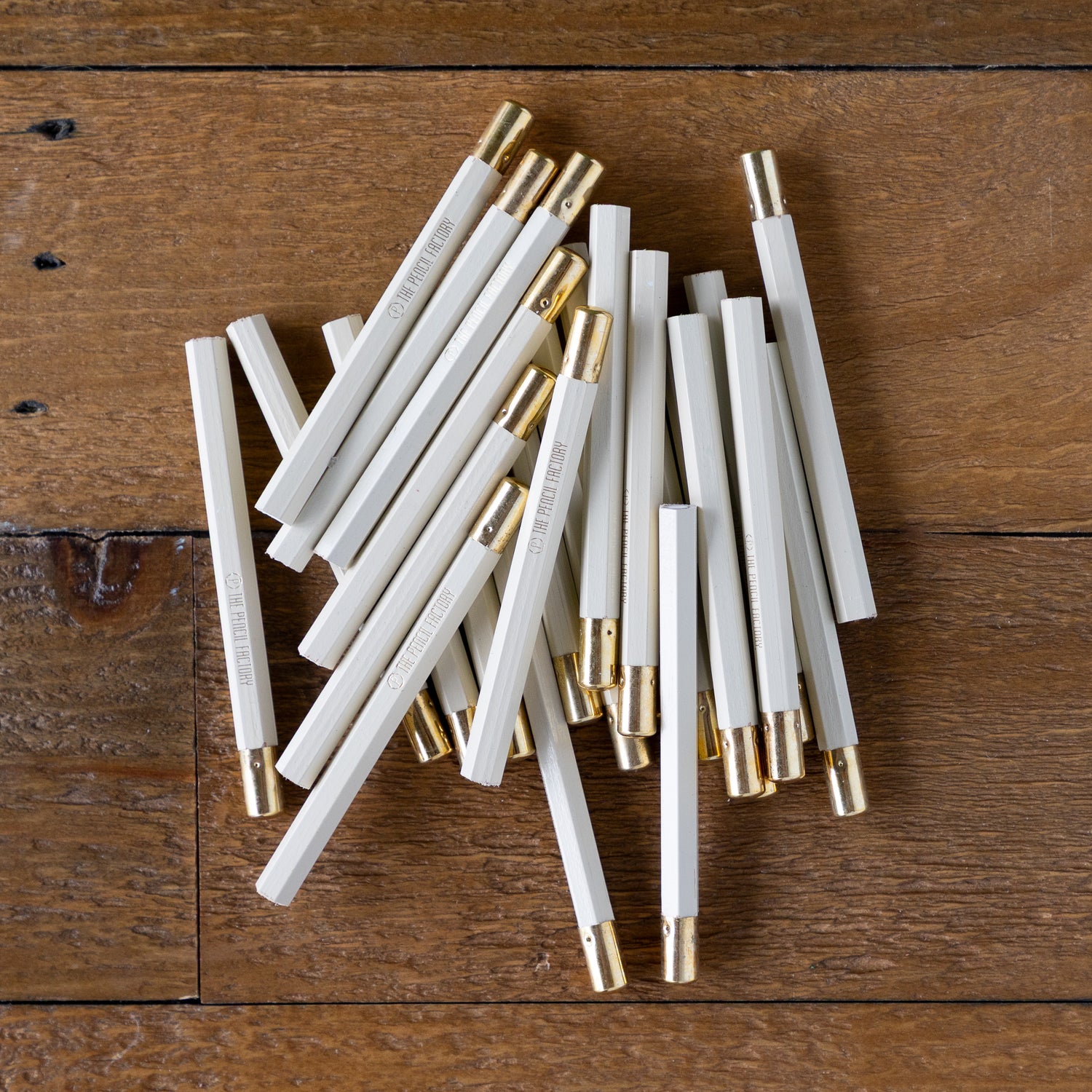 Mini Chalkboard Round Golf Pencils heaped together on a wood background. 