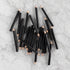 Mini Black Round Golf Pencils piled together on a marble background. 