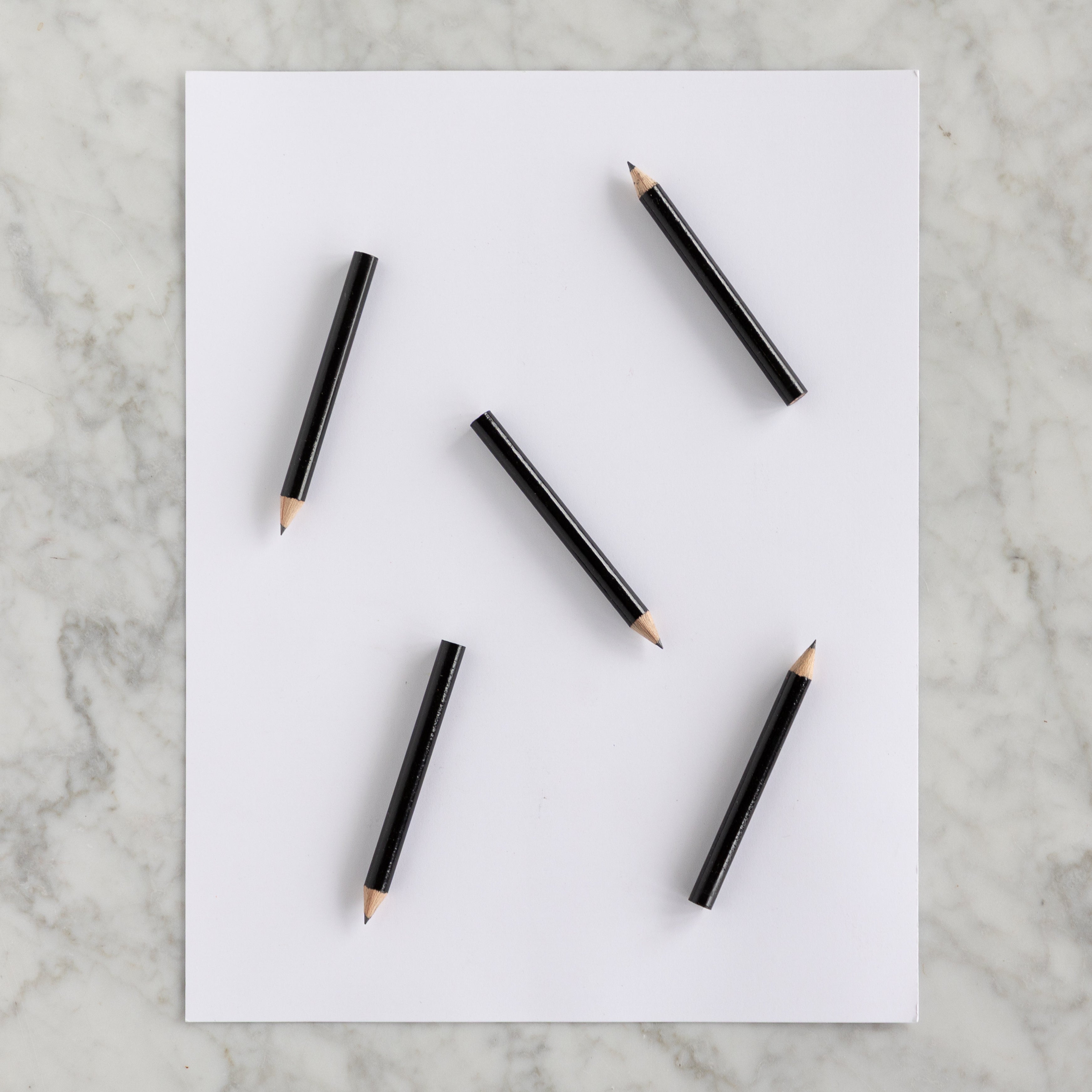 Five Mini Black Round Golf Pencils on a piece of paper. 